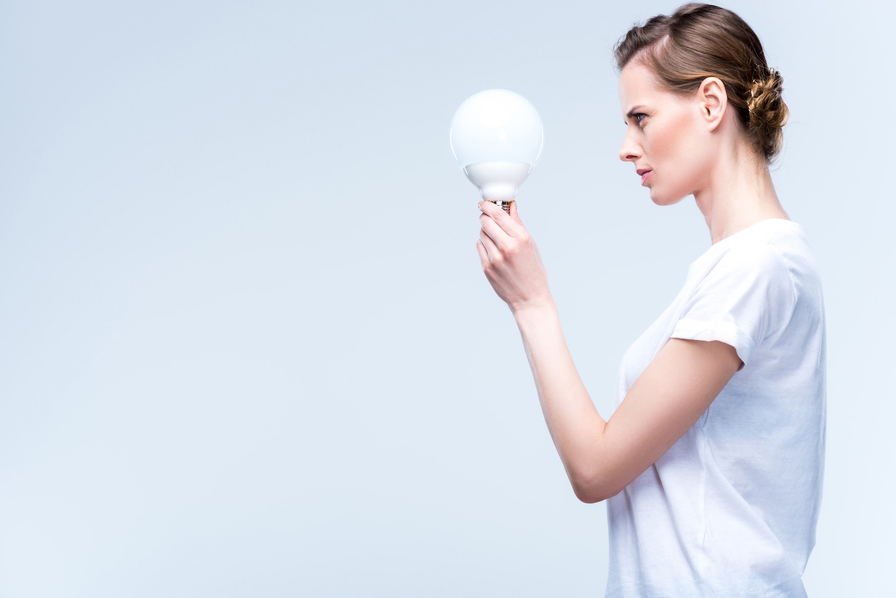 Woman focussing fully on lightbulb in her hand